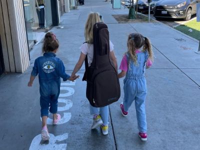 Dulcie Dornan is holding the hands of Elva and Alberta Dornan as they are walking.